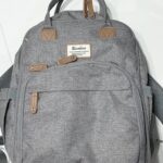 photo of the front of a grey backpack with tan leather zipper pulls